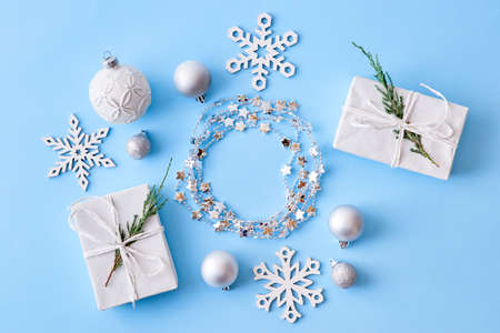 Flat lay christmas frame with snowflakes, balls and gift box on a blue background