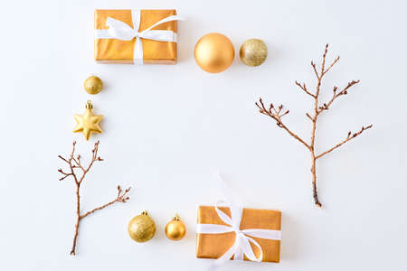 Flat lay frame with gold christmas balls, branches and gift box on a white background