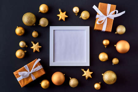 Mockup square white frame with gold christmas balls and gift box on a dark backgroundの写真素材