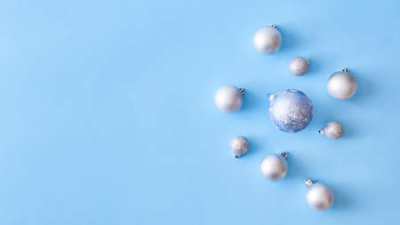 Flat lay christmas border with silver christmas balls on a blue background