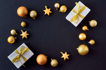 Flat lay frame with gold christmas balls and gift box on a dark background