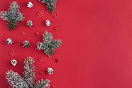 Flat lay christmas border with branches spruce and cones on a red background
