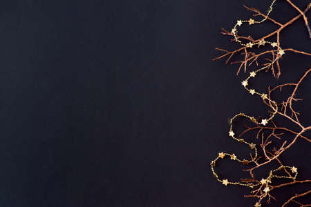 Flat lay border with gold christmas branch on a dark background