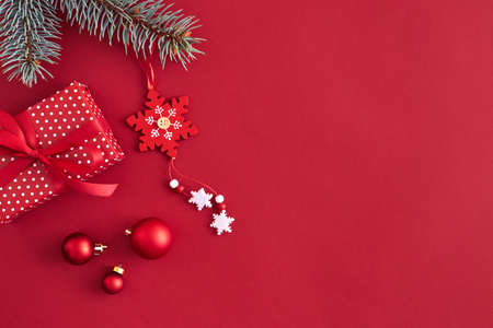 Flat lay border with branches spruce, red balls and christmas decoration on a red background