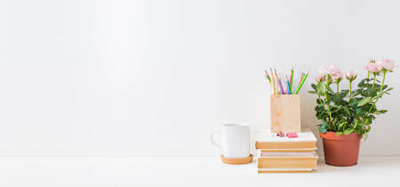 Home office, interior for bloggers workplace with roses in a pot, books, white mug, office suppliesの写真素材