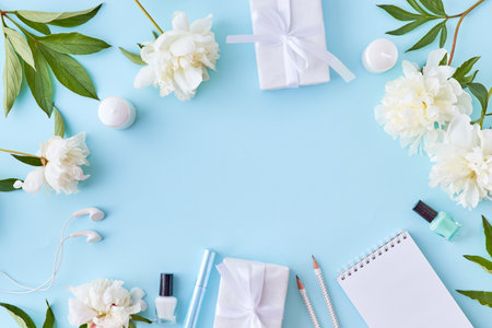 Flat lay blogger or freelancer workspace with a notebook and white peonies on a blue backgroundの写真素材
