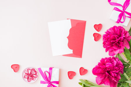 Mockup white greeting card and envelope with red peonies on a color backgroundの写真素材