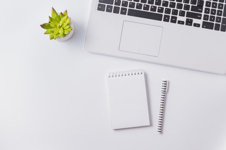 Flat lay composition with white laptop and mockup notepad on a white table