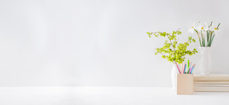 Home office, interior for bloggers workplace with white daffodils in a vase, office supplies on a light backgroundの写真素材