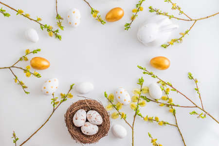 Flat lay easter composition with a willow branch and eggs on a white backgroundの写真素材