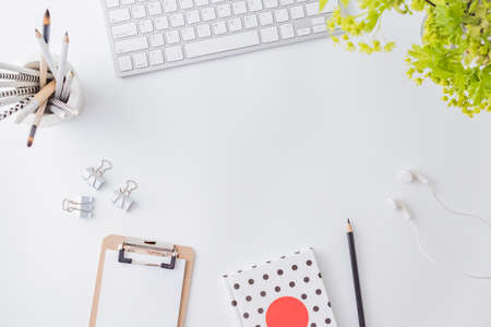 Flat lay blogger or freelancer workspace with a laptop, branches with green leaves, office supplies on a light backgroundの写真素材