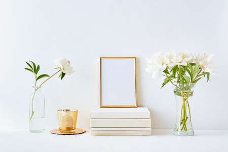 Home interior with decor elements. Gold frame, white peonies in a vase, interior decorationの写真素材