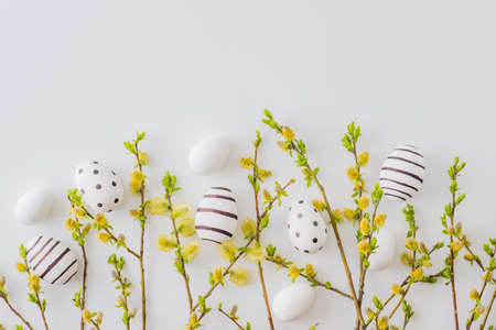 Flat lay easter composition with a willow branch and eggs on a white backgroundの写真素材