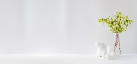 Home interior with easter decor. Spring flowers in a vases, easter eggs on a light backgroundの写真素材