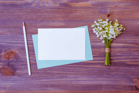 Mockup white wedding invitation and envelope with white flowers on a wooden background
