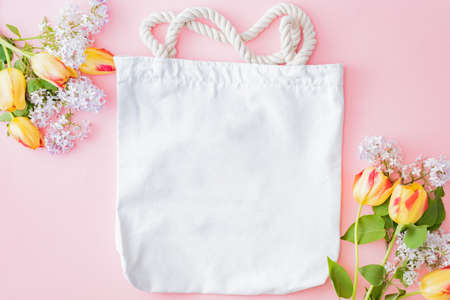 Mockup white bag with branches of lilac and yellow tulips on a pink backgroundの写真素材