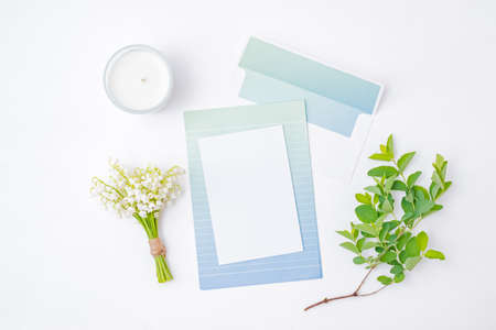 Mockup white wedding invitation and envelope with white flowers on a white backgroundの写真素材