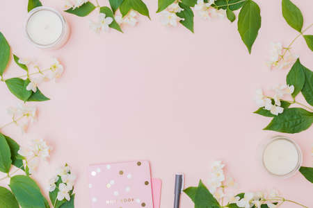 Flat lay composition with jasmine flowers, notebook on a pink background