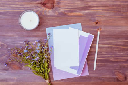 Mockup wedding invitation and envelope with blue flowers on a wooden tableの写真素材