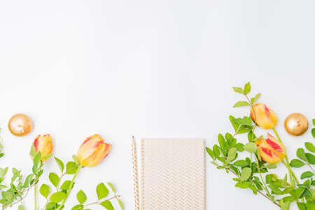 Flat lay blogger or freelancer workspace with a notebook and yellow tulips, branches with green...