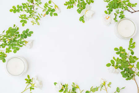 Flat lay composition with small flowers and green leaves on a light background