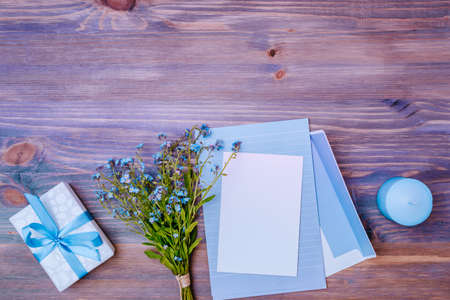 Mockup wedding invitation and envelope with blue flowers on a wooden table
