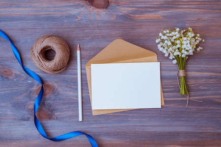 Mockup white wedding invitation and envelope with white flowers on a wooden backgroundの写真素材