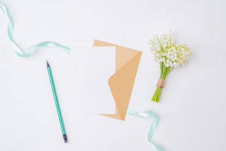 Mockup white wedding invitation and envelope with white flowers on a white backgroundの写真素材