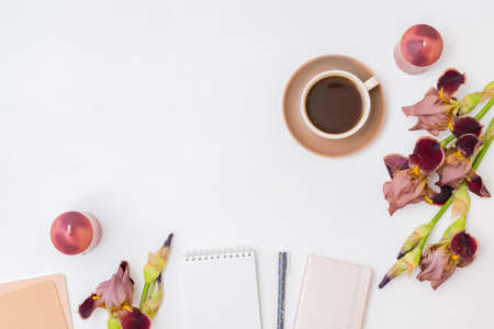 Flat lay composition with a cup of coffee and irises flowers on a white background