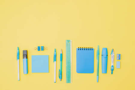 Flat lay border with school supplies on a yellow background