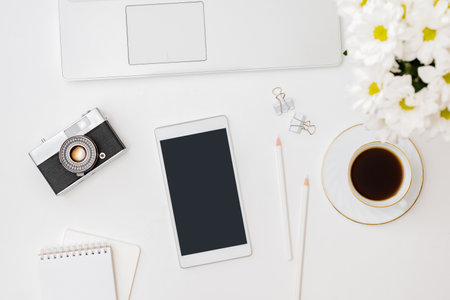 Flat lay mockup smartphone blank screen, laptop a cup of coffee on a white backgroundの写真素材