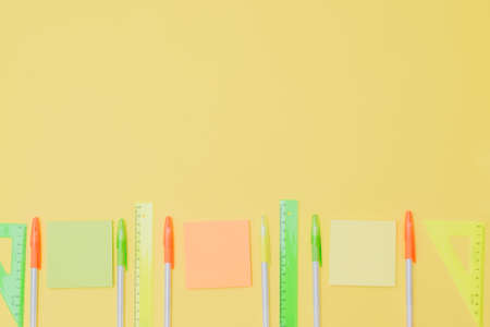 Flat lay border with school supplies on a yellow background