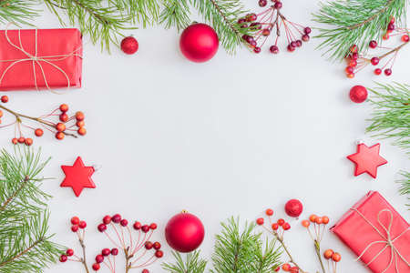 Flat lay frame with red christmas decoration, pine branches and gift box on a white background
