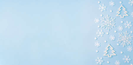 Flat lay border with snowflakes and christmas decoration on a blue background
