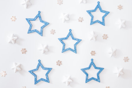 Flat lay pattern with stars, christmas baubles decoration and snowflakes on a white background