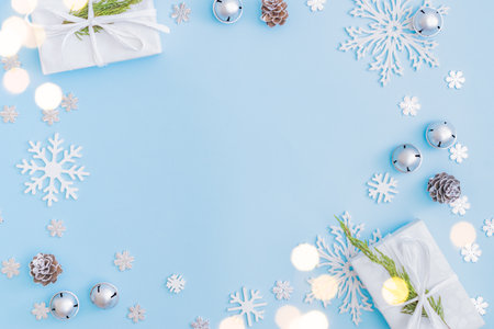 Flat lay christmas frame with snowflakes, balls and gift box on a blue backgroundの写真素材