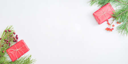 Flat lay frame with red christmas decoration, pine branches and gift box on a white backgroundの写真素材