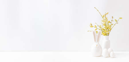 Home interior with easter decor. Willow branches in a vase, easter eggs on a light background