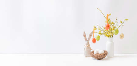 Home interior with easter decor. Willow branches in a vase, easter eggs on a light background