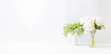Minimalist home interior with decor elements. White peonies in a vase on a light backgroundの写真素材