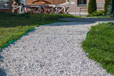 landscape design. Path of white small stones and green grass on a sunny dayの写真素材