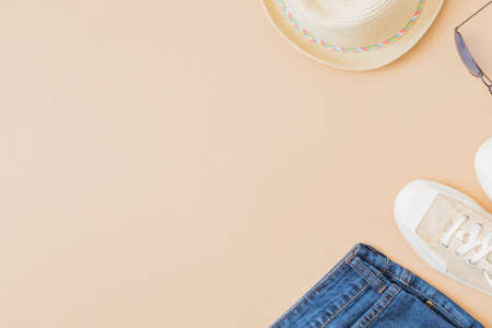 Flat lay summer composition with a straw hat, jeans and sneakers on a yellow backgroundの写真素材