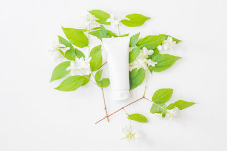 Flat lay beauty cosmetics tube branding mockup with jasmine flowers on a light backgroundの写真素材