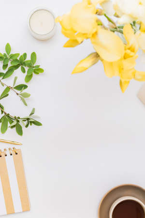 Flat lay home office desktop with notebook, yellow irises, cup with coffee on a white background