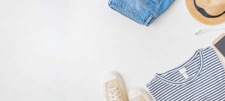 Flat lay summer composition with straw hat, jeans and sneakers on a white backgroundの写真素材