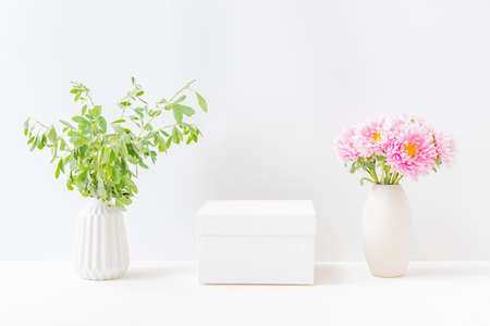 Empty white box and pink flowers in a vase on a light background. Mockup banner, podium for display of advertise productの写真素材