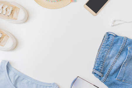 Flat lay summer composition with straw hat, jeans and sneakers on a white backgroundの写真素材