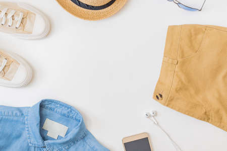 Flat lay summer composition with straw hat, denim and sneakers on a white backgroundの写真素材