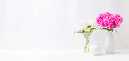 Minimalist home interior with decor elements. Pink peonies in a vase on a light backgroundの写真素材