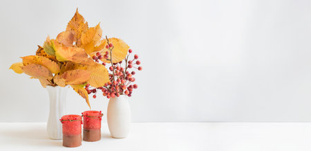 Home interior decor elements. Colorful autumn leaves in a vase on a light backgroundの写真素材